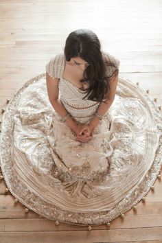 a woman sitting on top of a round rug in the middle of a wooden floor