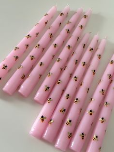 pink candles with bees on them are lined up