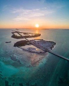 the sun is setting over an island in the middle of the ocean with water and land