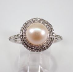 a pearl and diamond ring on a clear stand