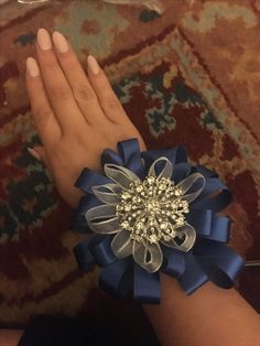 a woman's hand with a blue flower and crystal brooch on the wrist