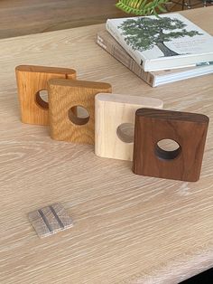 three wooden objects sitting on top of a table next to a book and some books