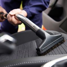 a person with a brush on top of a seat in the back of a car