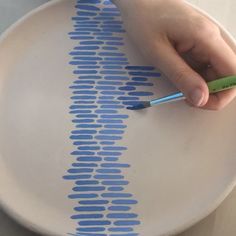 a person is drawing on a plate with blue and white lines that are drawn onto it