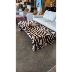 a zebra print coffee table sitting on top of a floor next to white couches