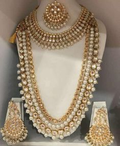 a white mannequin with pearls and gold jewelry on display in a shop window