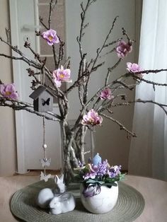 there is a vase with flowers in it and two bunny figurines on the table