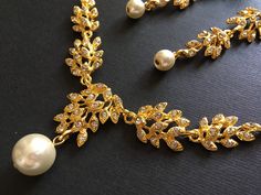 "** This listing including a necklace with a matching earrings (studs at back design). ** Romantic shaped gold plated necklace featuring clear rhinestones crystals and dangly with pearls at bottom. Perfect for your wedding wear!! Size: necklace measures around 15\" long x 1.45\" center drop. Earrings around 3\" long x 0.5\"width Color: gold with clear rhinestone crystals and pearls Item ship out in a gift box with tracking number to you (around 10 to 14 business days for delivery). We also provi Gold Rhinestone Crystal Necklace For Wedding, Elegant Gold Rhinestone Necklace For Wedding, Gold Bridal Necklace With Rhinestones For Wedding, Gold Rhinestone Necklaces For Wedding, Gold Rhinestone Necklace For Wedding, Bridal Necklace Gold, Chandelier Necklace, Gold Necklace Wedding, Bride Jewelry Set