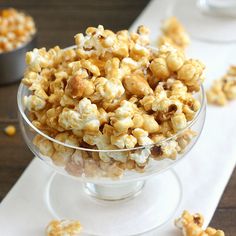 a glass bowl filled with popcorn sitting on top of a white tablecloth covered table