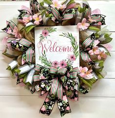 a welcome wreath with pink flowers and green leaves