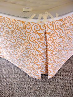 an orange and white table cloth on the floor