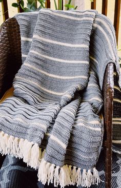 a chair with a blanket on top of it in front of a potted plant