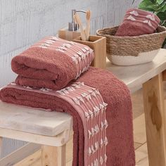 towels are stacked up on a bench next to a basket with utensils in it