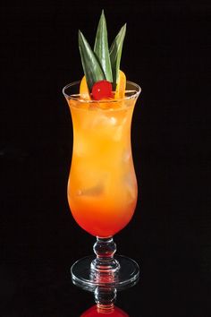 a tall glass filled with orange juice and garnished with a pineapple on top