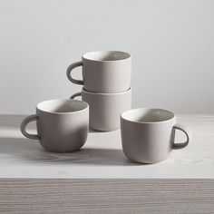 four white cups sitting on top of a wooden table