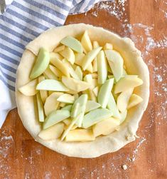 an uncooked apple pie sitting on top of a wooden table