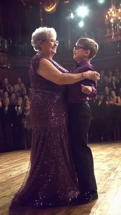 an older woman and young man dancing on a wooden floor in front of a crowd