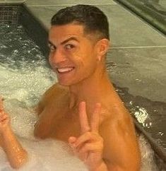 a man and woman in a hot tub giving the peace sign