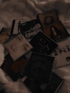 various cd's laying on top of a white fur covered bed next to each other