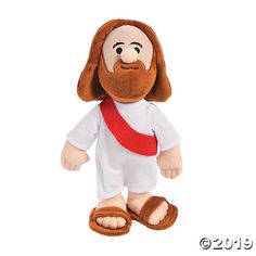 a stuffed jesus doll is wearing sandals and a white shirt with a red cross on it's chest