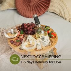 a tray with wine, cheese and grapes on it next to a pillow that says next day shipping