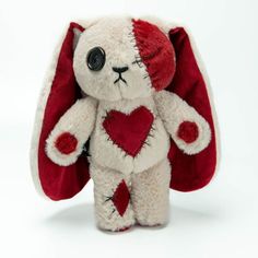 a white stuffed animal with a red heart on it's chest and ears is standing upright