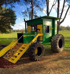 a tractor with a ramp attached to it in the middle of some grass and trees