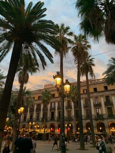 palm trees in front of a building with people walking around