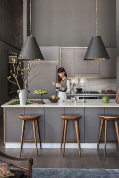 two people are in the kitchen and one person is sitting at the counter with food