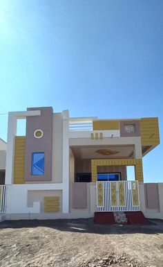 a white and yellow house sitting on top of a dirt field