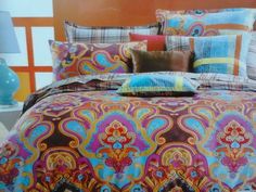 a bed with colorful comforters and pillows on it