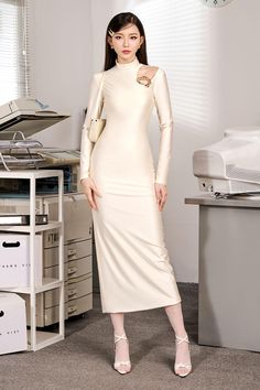 a woman is standing in an office wearing a white dress with long sleeves and high heels