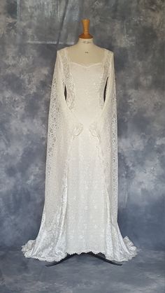 a white wedding gown on a mannequin with an open back and long sleeves