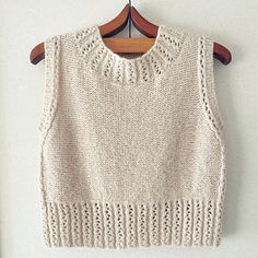 a white knitted sweater hanging on a wooden hanger