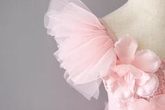 a dress with pink flowers on the back and tulle around the neck, sitting on a mannequin