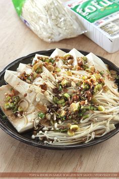 a black plate topped with noodles and vegetables next to a carton of yogurt