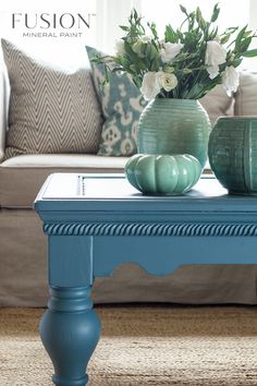 a blue coffee table with white flowers in a vase on top and the words seaside painted over it