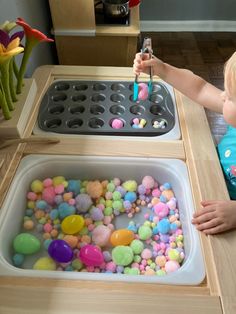 a toddler playing with play dough and candy in a toy kitchen area that includes an ice cream maker