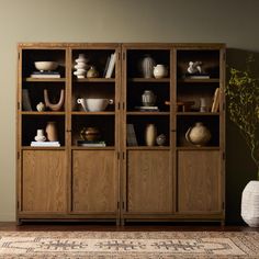 a wooden bookcase filled with lots of books and vases on top of it