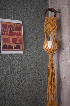 a yellow rope hanging from the side of a wall next to a piece of art