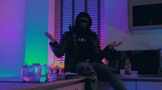 a person in a black hoodie sitting on a counter with their hands out to the side