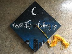 a graduation cap with the words never stop looking up and a tassel hanging from it