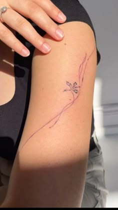 a woman's arm with a small flower tattoo on the left side of her arm