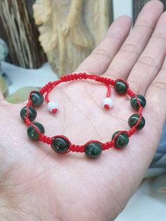 9 pcs of black-green Jade beads, 9 mm to 10 mm in size, woven together to make this beautifully handcrafted Red Thread Bracelet which we have braided ourselves. Size adjustable and the pair of white Jade beads at the adjusters complete a visually pleasing, tricolor contrast (black, red & white). All Jade components are Type A natural Jadeite (non-bleached, non-dyed, non-treated materials). For customers with much bigger fist and wrist, you can send us a direct message after your payment so we can customized the size before shipping. Handmade Red Jade Bracelets, Adjustable Red Jade Bracelet, Green Hand-strung Braided Bracelet With Round Beads, Green Hand-strung Braided Bracelets, Green Braided Bracelets With Round Beads, Handmade Green Braided Bracelets With Round Beads, Black Jade Bracelets Gift, Green Bracelets With Black Beads As Gift, Green Beaded Bracelets With Black Beads As A Gift