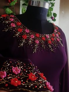 a purple dress with red flowers and beads on the neckline is displayed in front of a mannequin