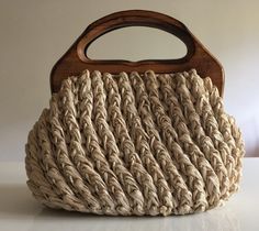 a handbag made out of jute is sitting on a white surface with a wooden handle