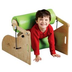 a young boy is smiling while playing with a wooden swing and slide set in the shape of a house