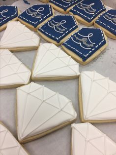 some cookies are laying on a table with blue and white icing, along with other decorated cookies