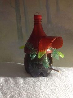 a red bottle sitting on top of a table next to a white cloth covered wall