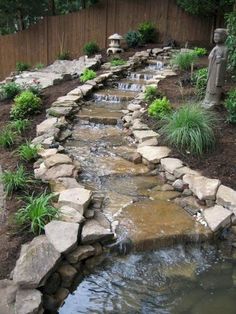 a garden with rocks and water features a small waterfall in the center, surrounded by greenery